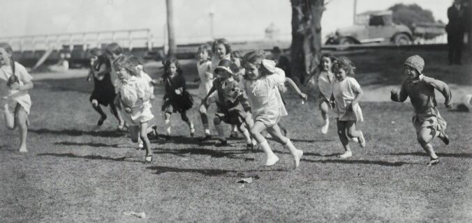 Kinder laufen gemeinsam über eine Wiese – spielerische Leichtathletik